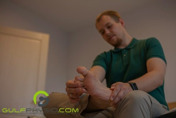 A man is sitting down and massaging his foot.